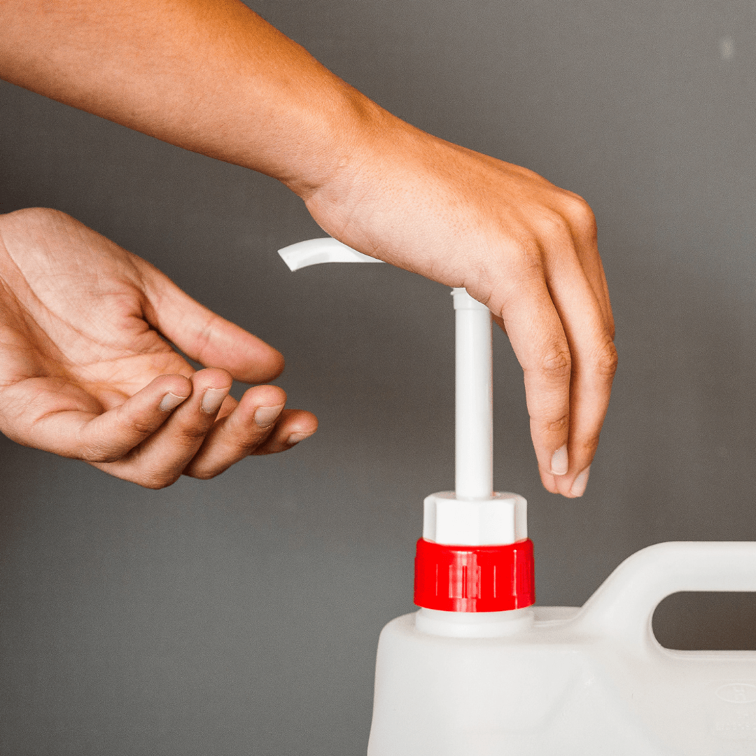 Mão a segurar na bomba doseadora EcoX colocada num garrafão 5L de detergente EcoX