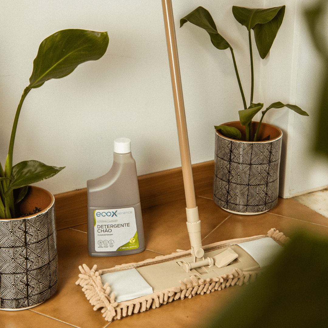 Embalagem de detergente chão alfazema EcoX 850mL no chão ao lado da esfregona e de plantas
