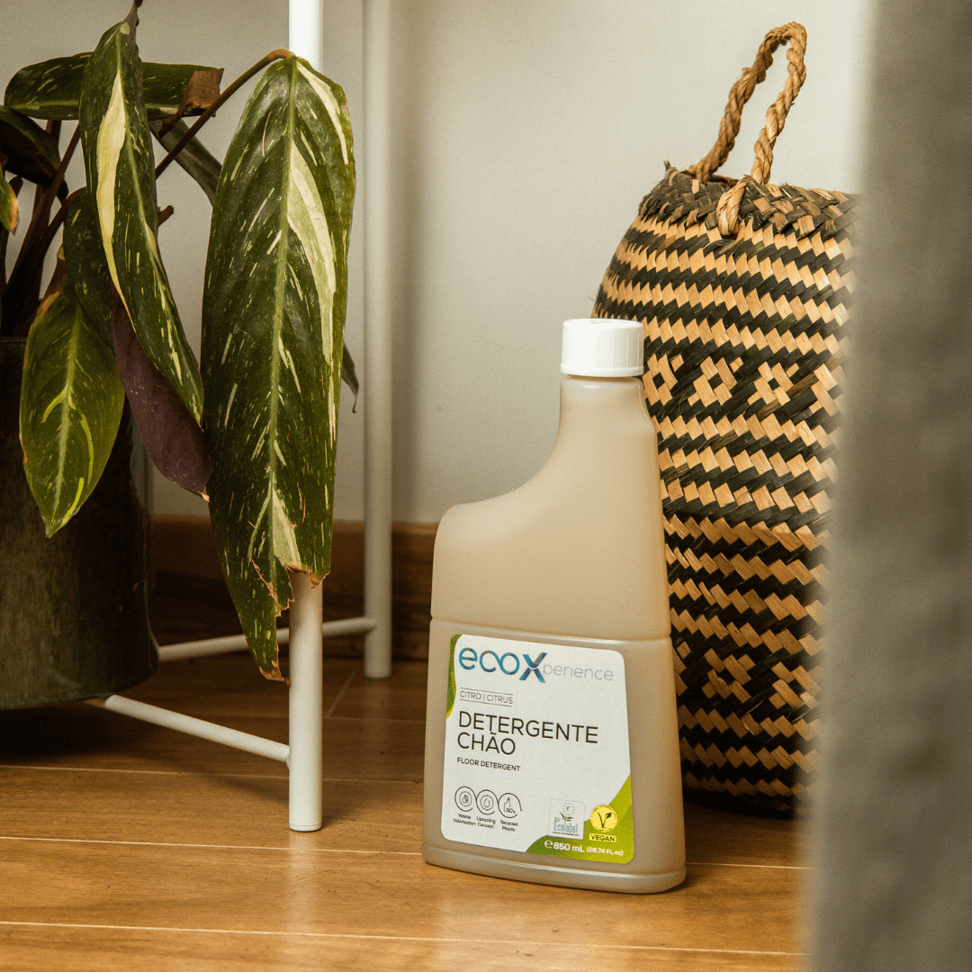 Embalagem de detergente chão citro EcoX 850mL ao lado de uma cesta e uma planta