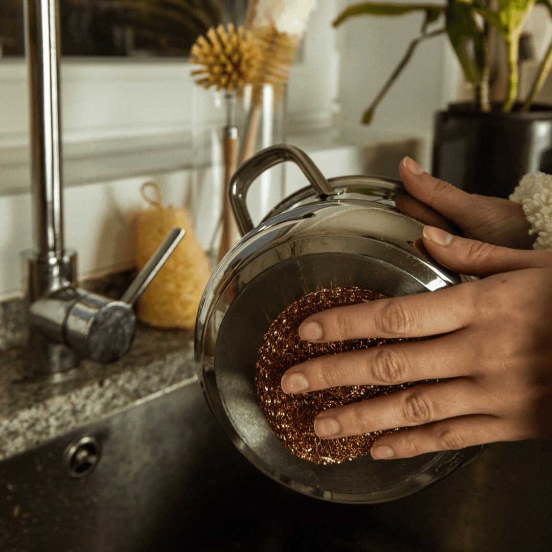 Mão a passar o esfregão da loiça EcoX no tacho