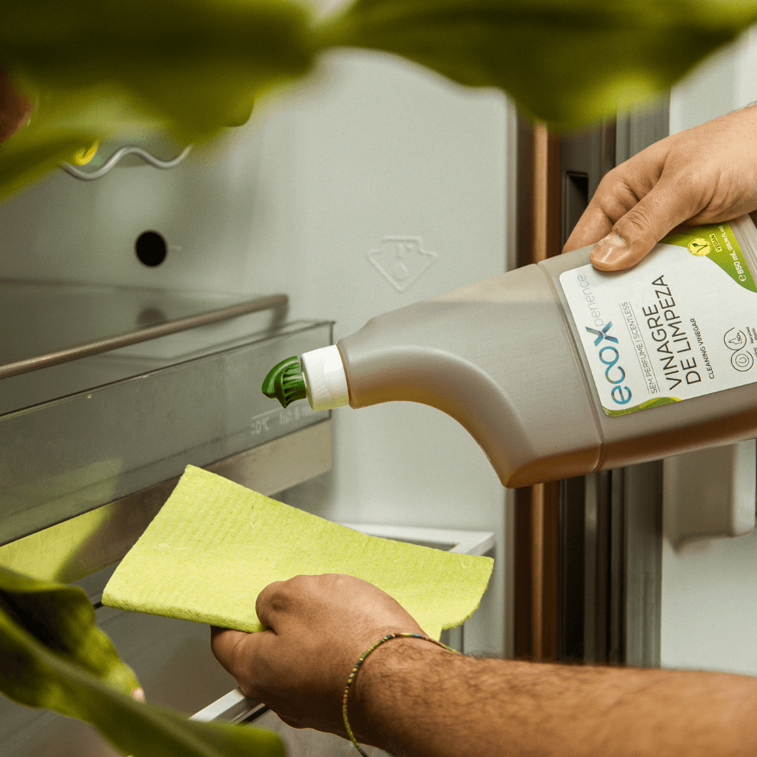 Mão a deitar vinagre de limpeza EcoX na esponja de celulose