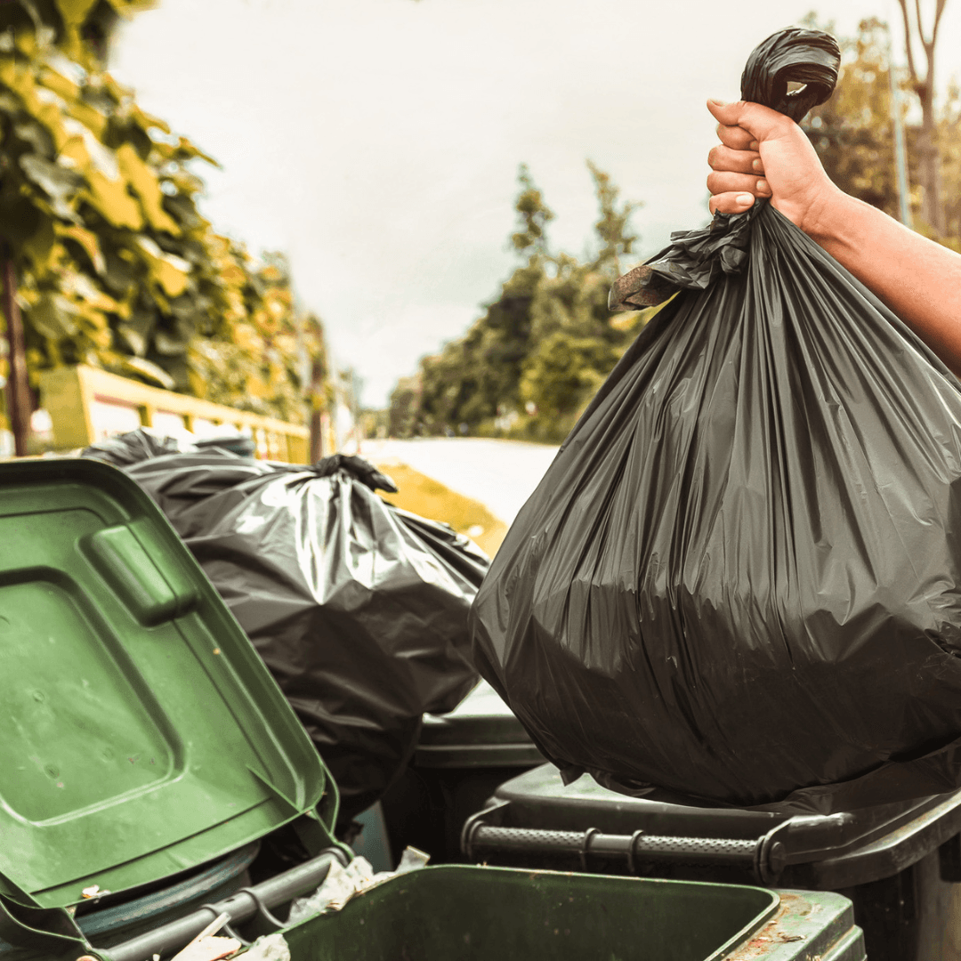 Pessoa a colocar no contentor um saco de lixo ecológico