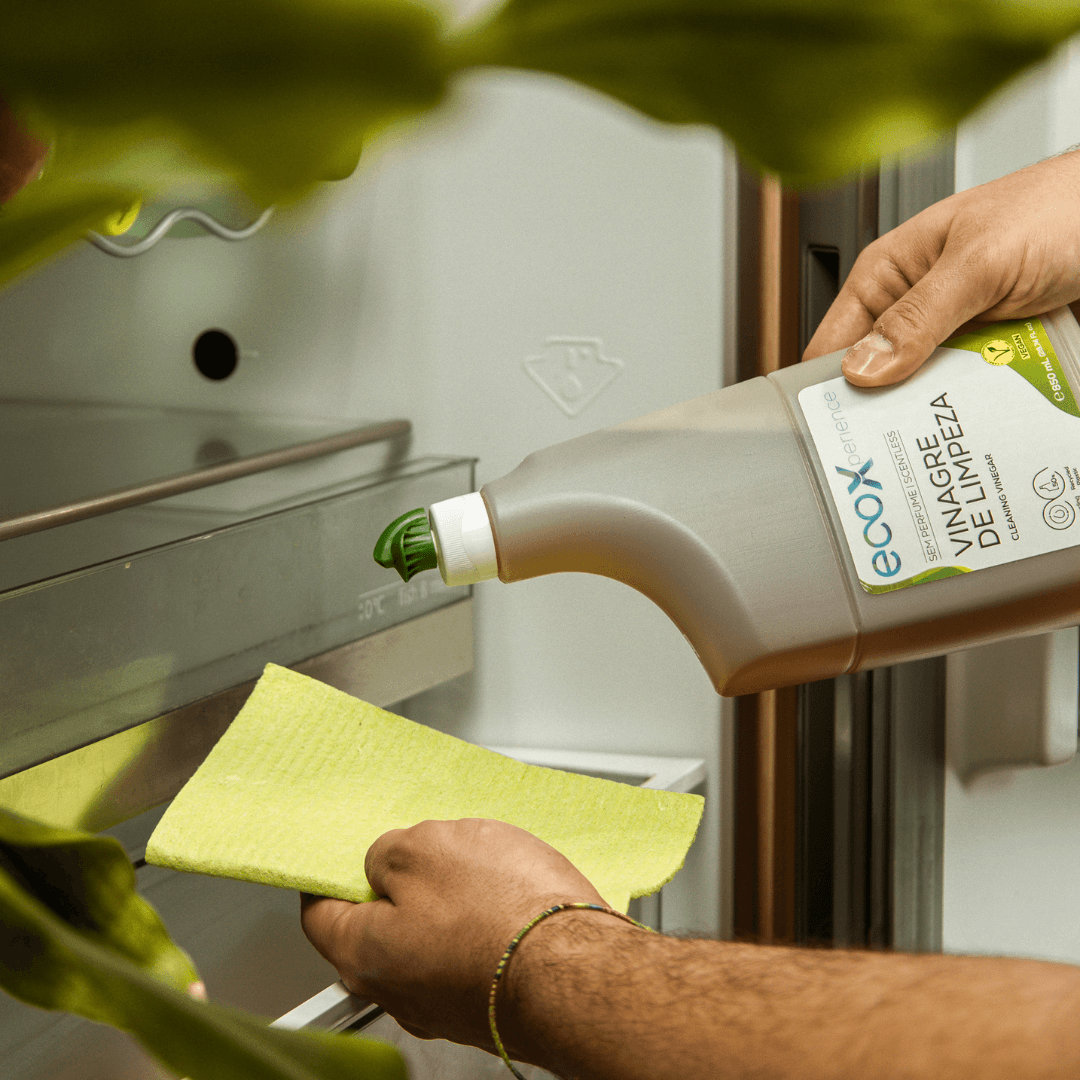 Mão a colocar vinagre de limpeza EcoX 850mL num pano para limpar o frigorífico