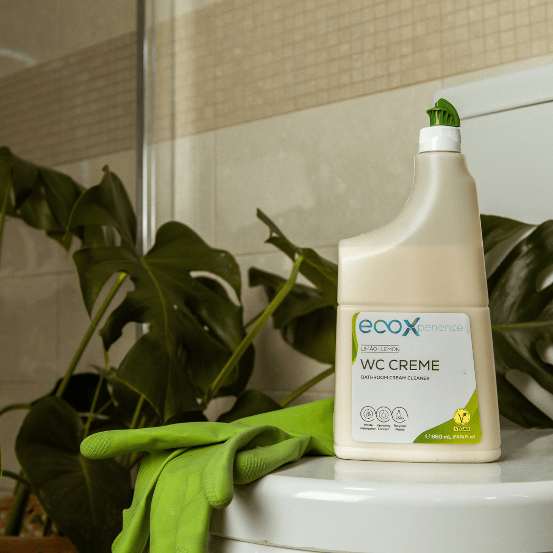 Embalagem de WC creme EcoX 850mL em cima do tampo da sanita ao lado de luvas latex ecológico