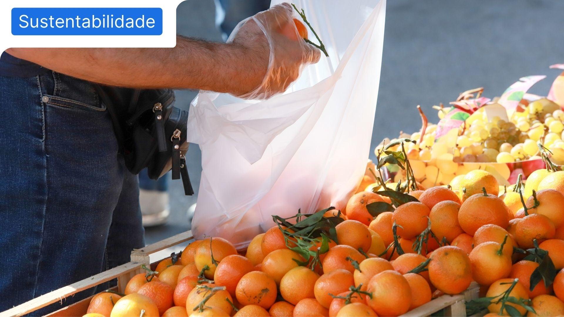 Mão de pessoa a colocar fruta num saco para retratar o tema da importância de comprar produtos portugueses