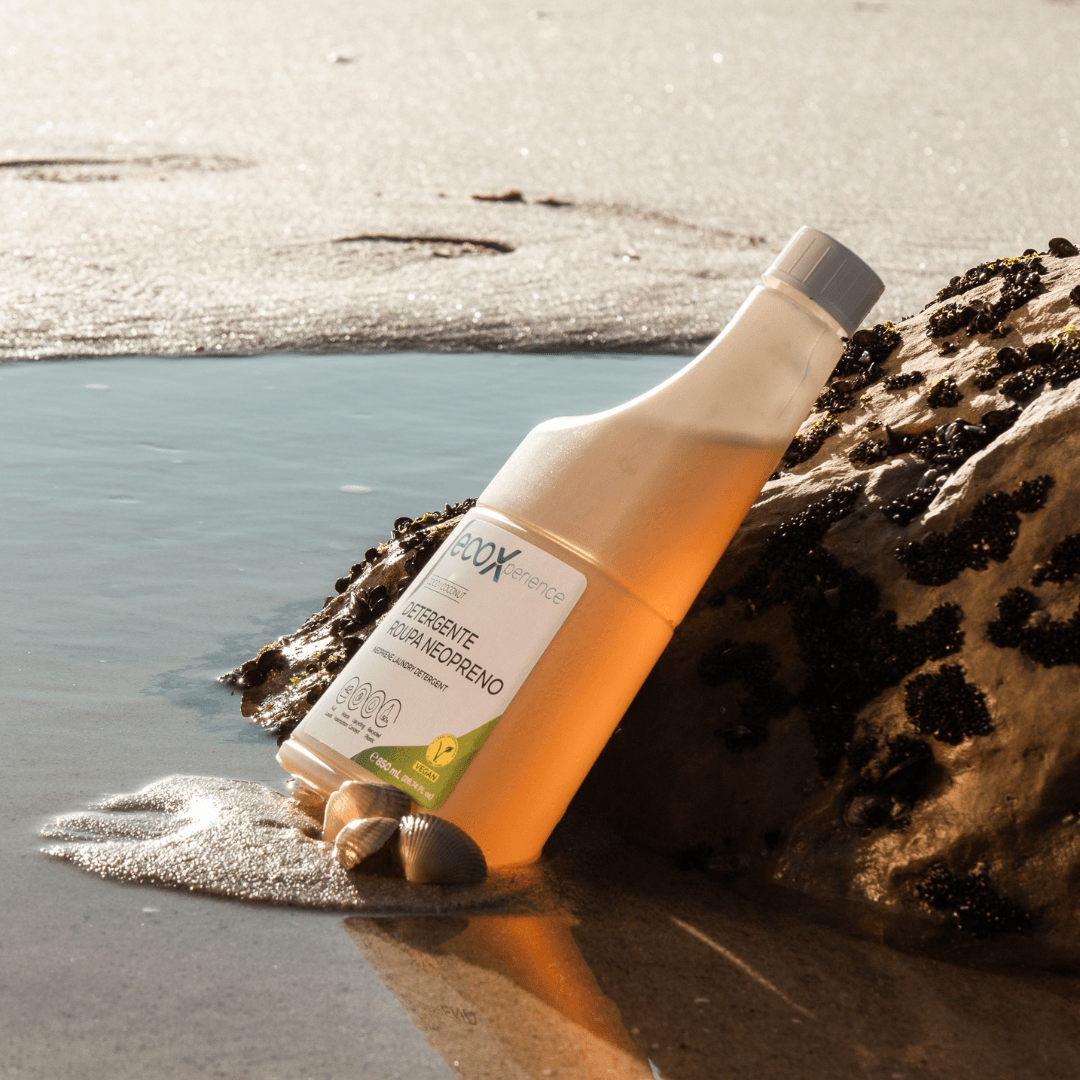 Embalagem de detergente neopreno EcoX 850mL encostado a uma rocha perto do mar