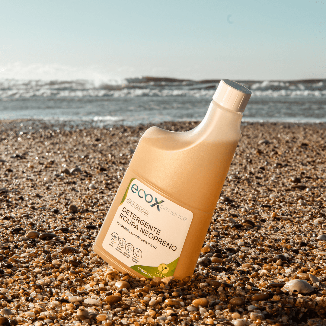 Embalagem de detergente neopreno EcoX 850mL na areia com o mar atrás